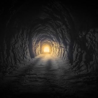Dunkler Felstunnel mit warmem Licht am Ende – Sinnbild dafür, durch die Angst hindurchzugehen